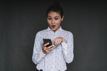 Surprised Asian female using smartphone