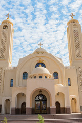 Coptic Orthodox Church in Sharm El Sheikh, Egypt.Against the backdrop of a beautiful sky with clouds. All Saints Church. Concept of the righteous faith. vertical photo