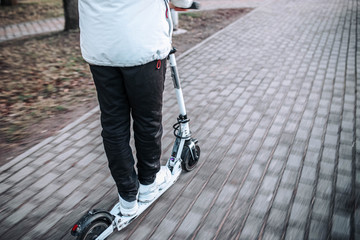 man rides a white electric scooter on a frosty winter day. Electric transport.
