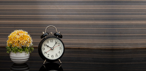 Naklejka premium Vintage style alarm clock on wooden background banner with copy space