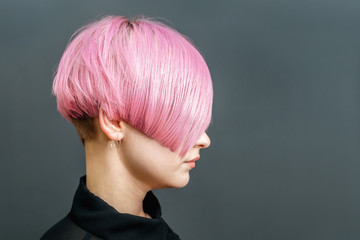 Beautiful model woman with short pink hairstyle on gray background.