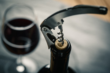 Stainless  wine corkscrew in a cork of wine bottle neck on a black slate background