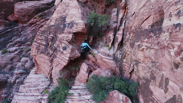 Female rock climber hikes and scrambles up boulders at Red Rock Canyon cliffs