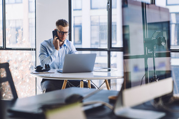 Puzzled manager talking on smartphone in office