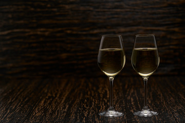 two glasses of  white wine on a black wooden background, with copy space.