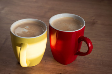Two cups of cappuccino with latte art on wooden background. Beautiful foam, greenery ceramic cups, stylish toning, place for text.