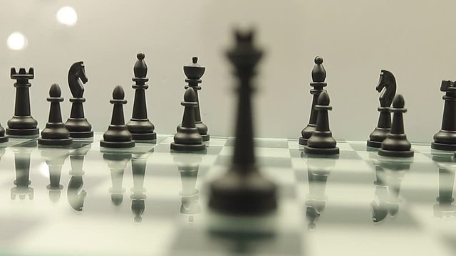 change of focus from the black king on the chessboard to other black pieces on a white background