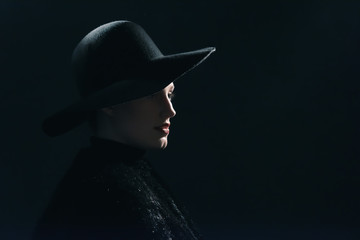 Vintage 1940s woman in black hat. Side view.