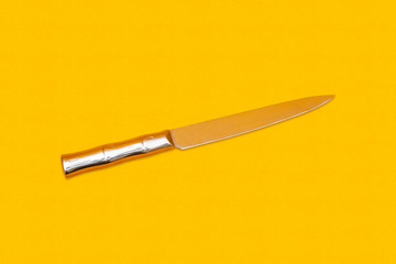 Close up photo of silver knife top view on yellow background