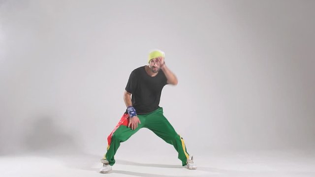 Delighted bright male dancer dressed in sportive clothes, showing street dance element in studio