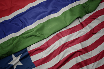 waving colorful flag of liberia and national flag of gambia.