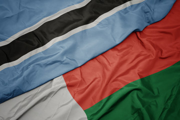 waving colorful flag of madagascar and national flag of botswana.