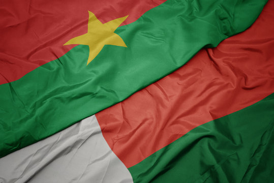 waving colorful flag of madagascar and national flag of burkina faso.