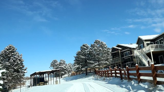 POV of a snowy urban scene in Winter, snow covered houses and trees, Moving Forward