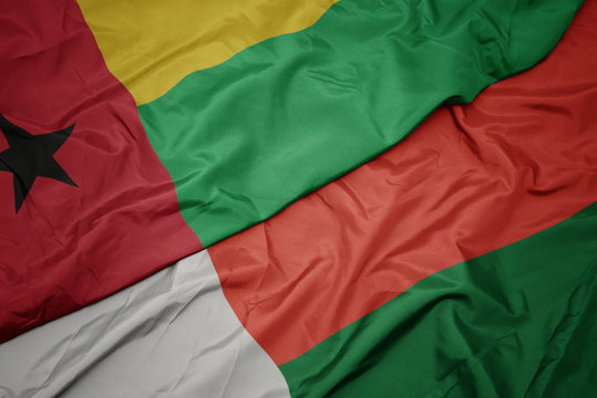 waving colorful flag of madagascar and national flag of guinea bissau.