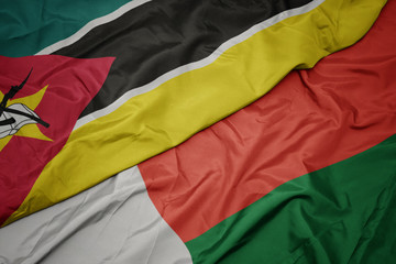 waving colorful flag of madagascar and national flag of mozambique.