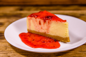 White plate with cheesecake New York and raspberry jam on wooden table