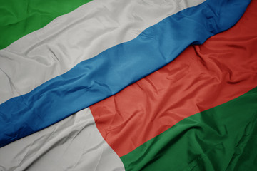 waving colorful flag of madagascar and national flag of sierra leone.