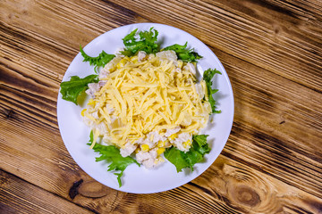 Festive salad with chicken breast, canned pineapple, cheese, sweet corn and mayonnaise on wooden table. Top view