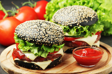 Two black burgers with vegetables and beef meat	