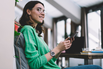 Smiling young woman in green sweater with smartphone