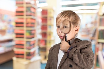 Little schoolboy in glasses on library