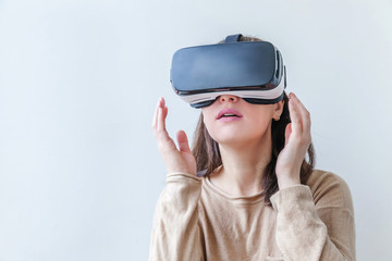 Smile young woman wearing using virtual reality VR glasses helmet headset on white background. Smartphone using with virtual reality goggles. Technology, simulation, hi-tech, videogame concept.