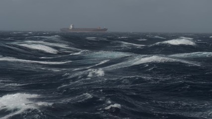 Large container ship heading in rough sea on tailwind