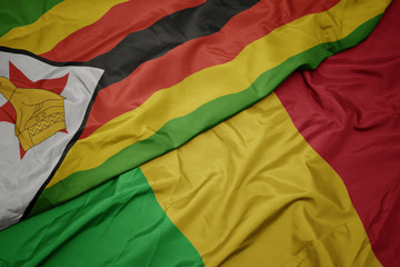 waving colorful flag of mali and national flag of zimbabwe.