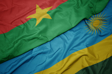 waving colorful flag of rwanda and national flag of burkina faso.