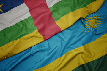 waving colorful flag of rwanda and national flag of central african republic.