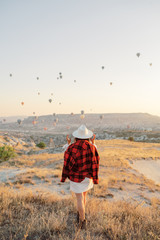 Obraz premium Woman watching colorful hot air balloons flying over the valley at Cappadocia, Turkey.Turkey Cappadocia fairytale scenery of mountains. Turkey Cappadocia fairytale scenery of mountains