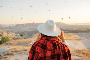 Woman watching colorful hot air balloons flying over the valley at Cappadocia, Turkey.Turkey Cappadocia fairytale scenery of mountains. Turkey Cappadocia fairytale scenery of mountains