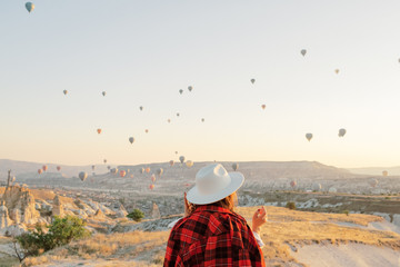 Woman watching colorful hot air balloons flying over the valley at Cappadocia, Turkey.Turkey Cappadocia fairytale scenery of mountains. Turkey Cappadocia fairytale scenery of mountains