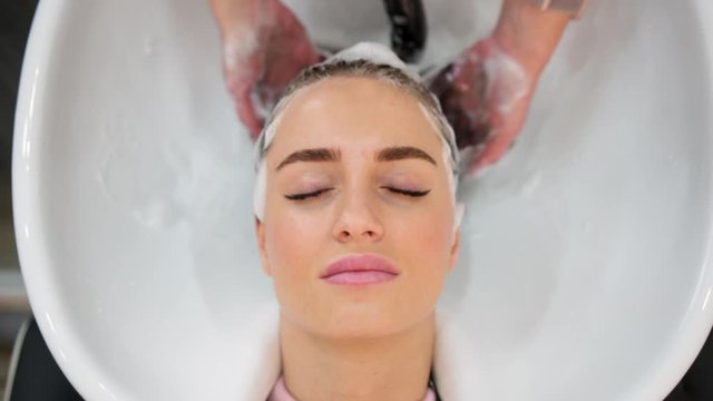 Close up of master hairdresser washing woman hair in beauty salon