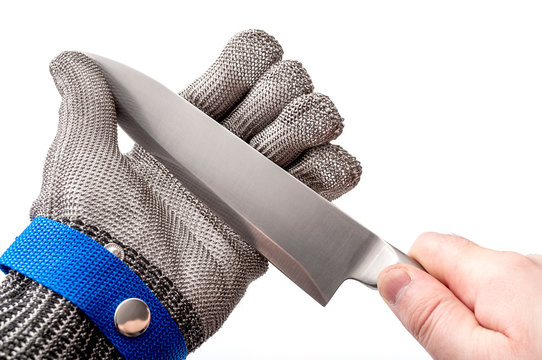 Work safety and protective gear for safe working environment conceptual idea with hand wearing metal mesh protection glove and holding stainless steel knife by the blade isolated on white background