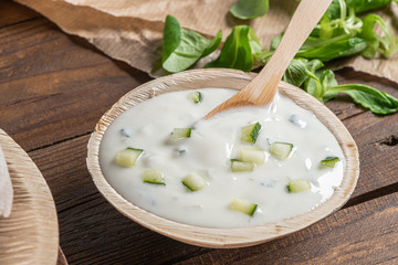 Top view of wooden cutting board on old wooden table top with tablecloth and yogurt sauce dip in a bowl