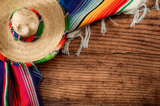 Celebrating Cinco de Mayo and Mexican fiesta conceptual idea with authentic hat (sombrero) and traditional colourful rug (serape) on wood background with copy space