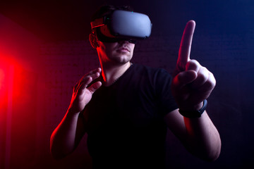 Fototapeta na wymiar man in modern wireless glasses of virtual reality against a dark background, a guy touches the virtual world