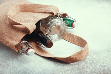 Reusable glass bottles and jars in burlap bag. Sustainable lifestyle. Zero waste grocery shopping...