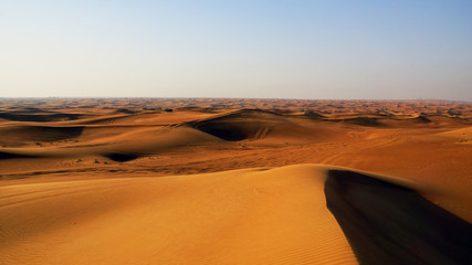 Fototapeta na wymiar red sand dunes in the desert of the United Arab Emirates, blue sky in the backgrpound