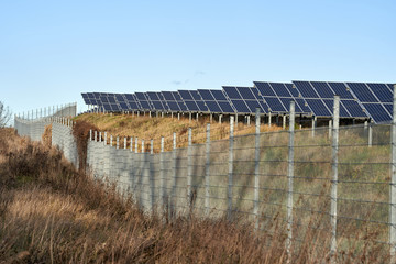 Fototapeta premium green energy. solar panel field in the winter sun behind a fence. alternate energy. photovoltaic, blue sky, germany 