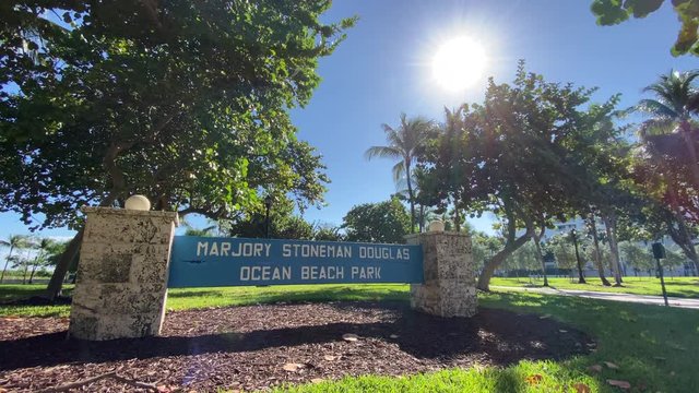 A daytime wide exterior establishing shot of the entrance to Marjory Stoneman Douglas Ocean Beach Park in Miami Beach.  	