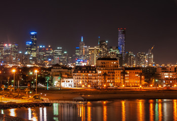 Fototapeta na wymiar Melbourne, Australia - December 18, 2009: Port Melbourne beach area and Phillip bay at night offers light show with skyscrapers such as Eureka Tower and more in back under pick black sky. 
