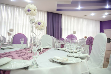 close up photo of a white arranged table with lila details in a wedding banquet hall