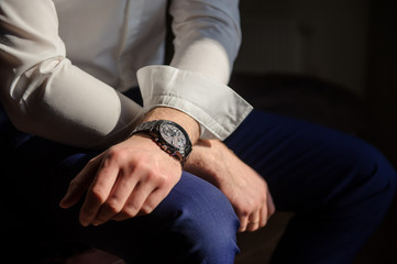 close up photo of groom's hands in a suit, a watch on the left hand