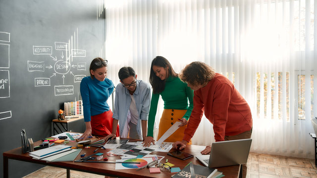 Brainstorming. Professional team of young web designers working on a new project together and discussing ideas while standing in the modern and bright office