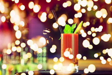 Bloody Mary at the bar counter. Classic cocktail. Dark background. Horizontal, lightly toned with festive holiday bokeh