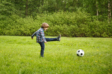 Naklejka premium Sports Kid. Baby playing soccer ball in the park. Children play football. Family leisure.