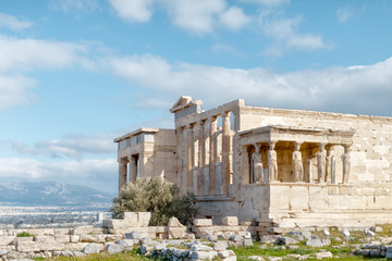 Obraz premium Panoramic view on the ruins of Erechtheion temple. Acropolis Hill in Athens. The surviving part of the colonnade. Figures of Caryatids Porch. Female statues. Blue sky. Traveling and vacation concept.